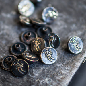 Pile of brass buttons with a creature printed on them