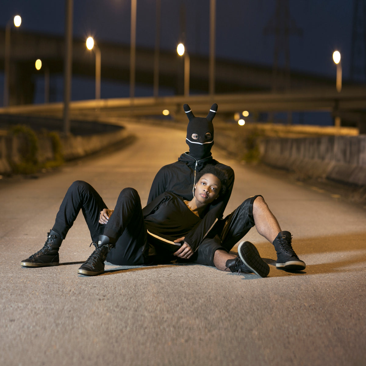 Two people in dark clothing sitting on a road at night.
