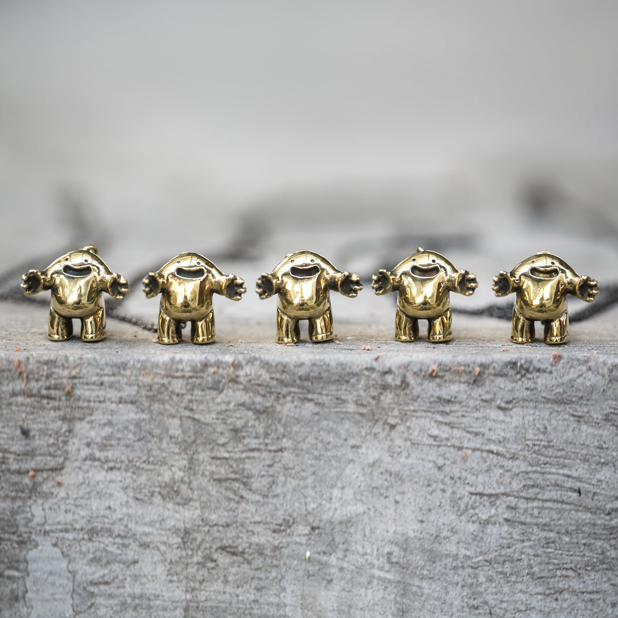 Five small gold rounded figurine statues standing on a textured surface with a blurred background