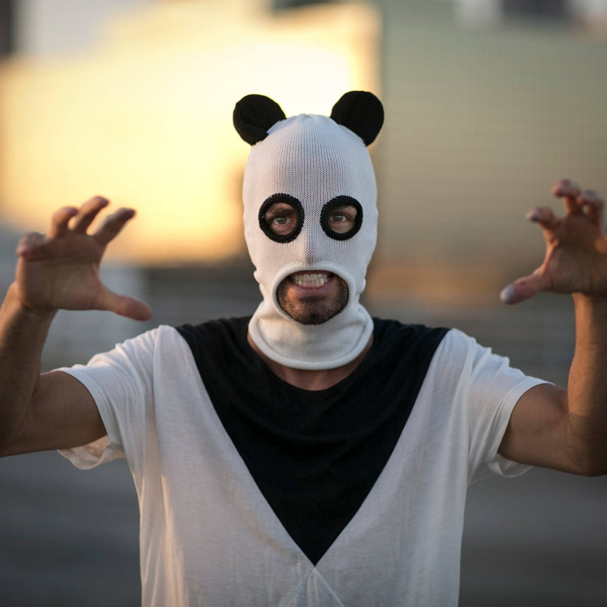 Person wearing a panda mask with arms outstretched against a blurred background