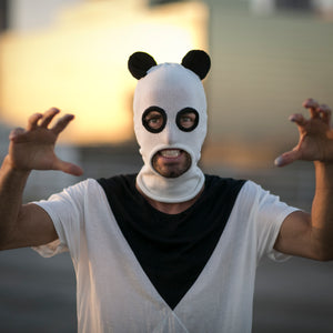 Person wearing a panda mask with arms outstretched against a blurred background