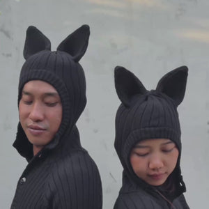 Two people wearing Bat onesies  against a light gray background