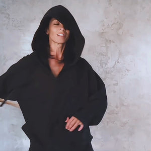 Person in a black hoodie with the hood on swinging around a wooden stick