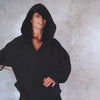 Person in a black hoodie with the hood on swinging around a wooden stick