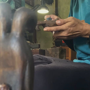 Person hand crafting a wooden bunny statuette 