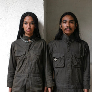 Two people in jumpsuits showing the magnetic pockets and other functions against a gray textured background 