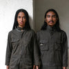 Two people in jumpsuits showing the magnetic pockets and other functions against a gray textured background 