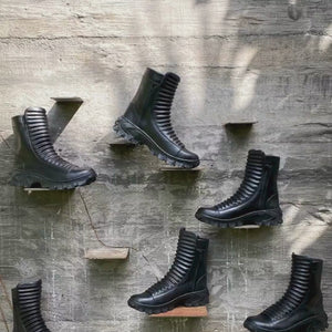 Person hand crafted and painting black ridged leather boots