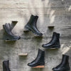 Person hand crafted and painting black ridged leather boots