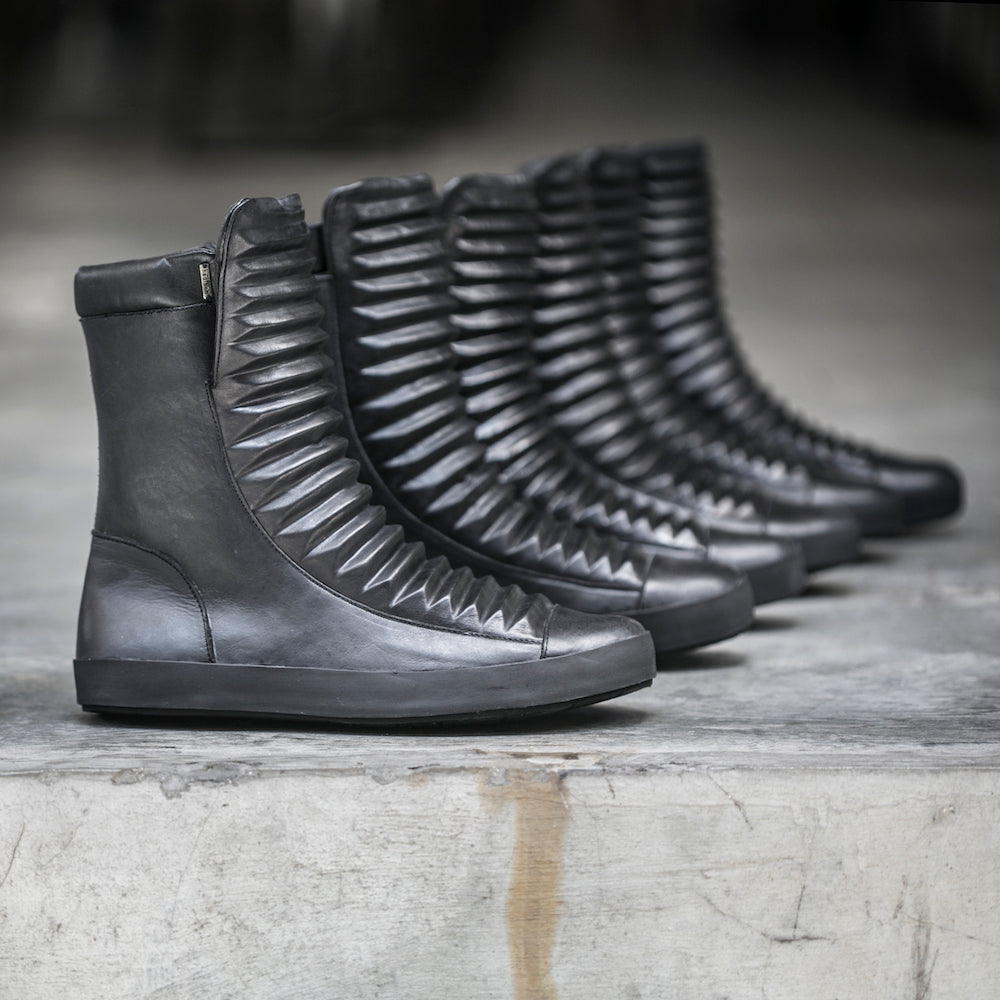 Row of black leather boots on a textured surface