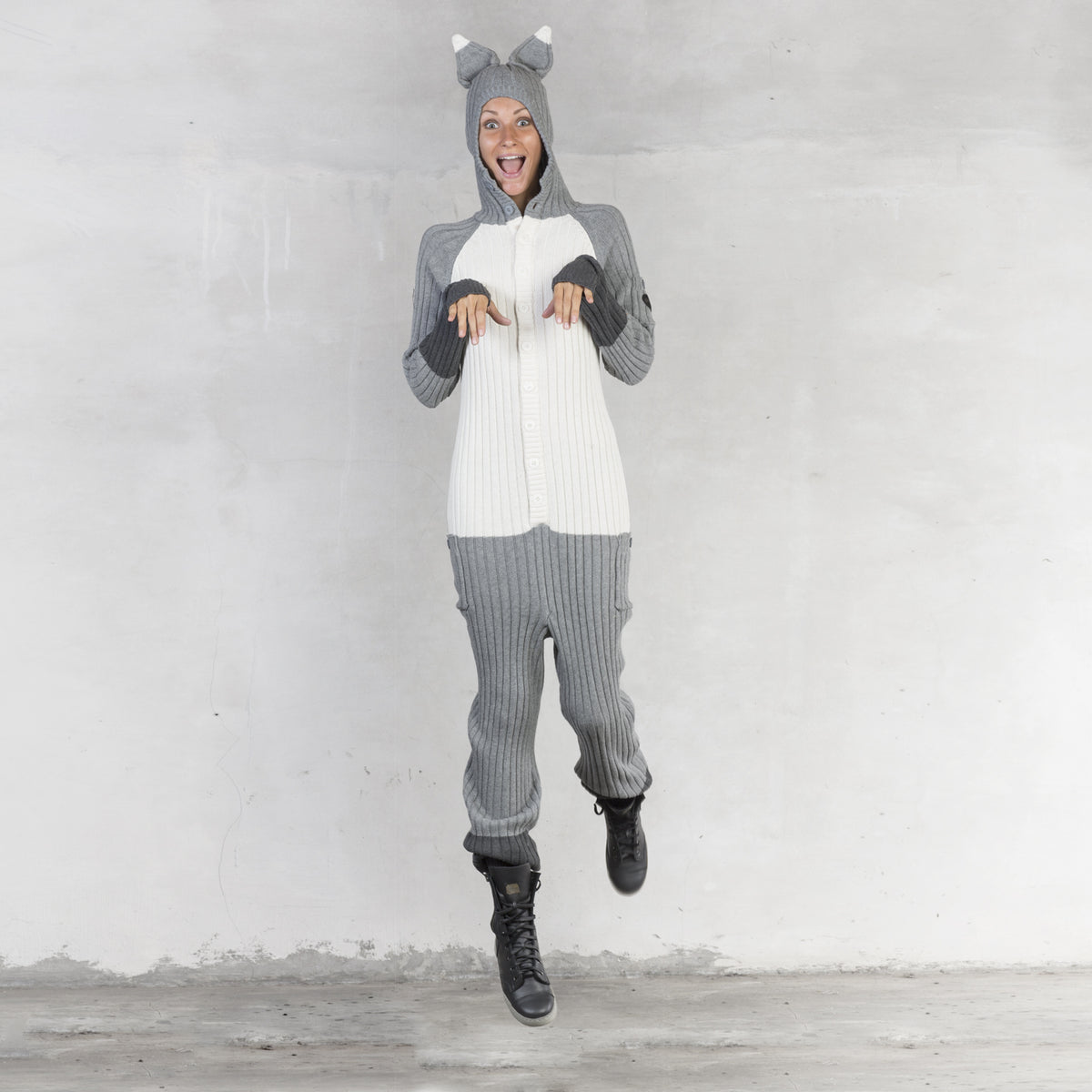 Person wearing a gray and white onesie with a hood against a plain background