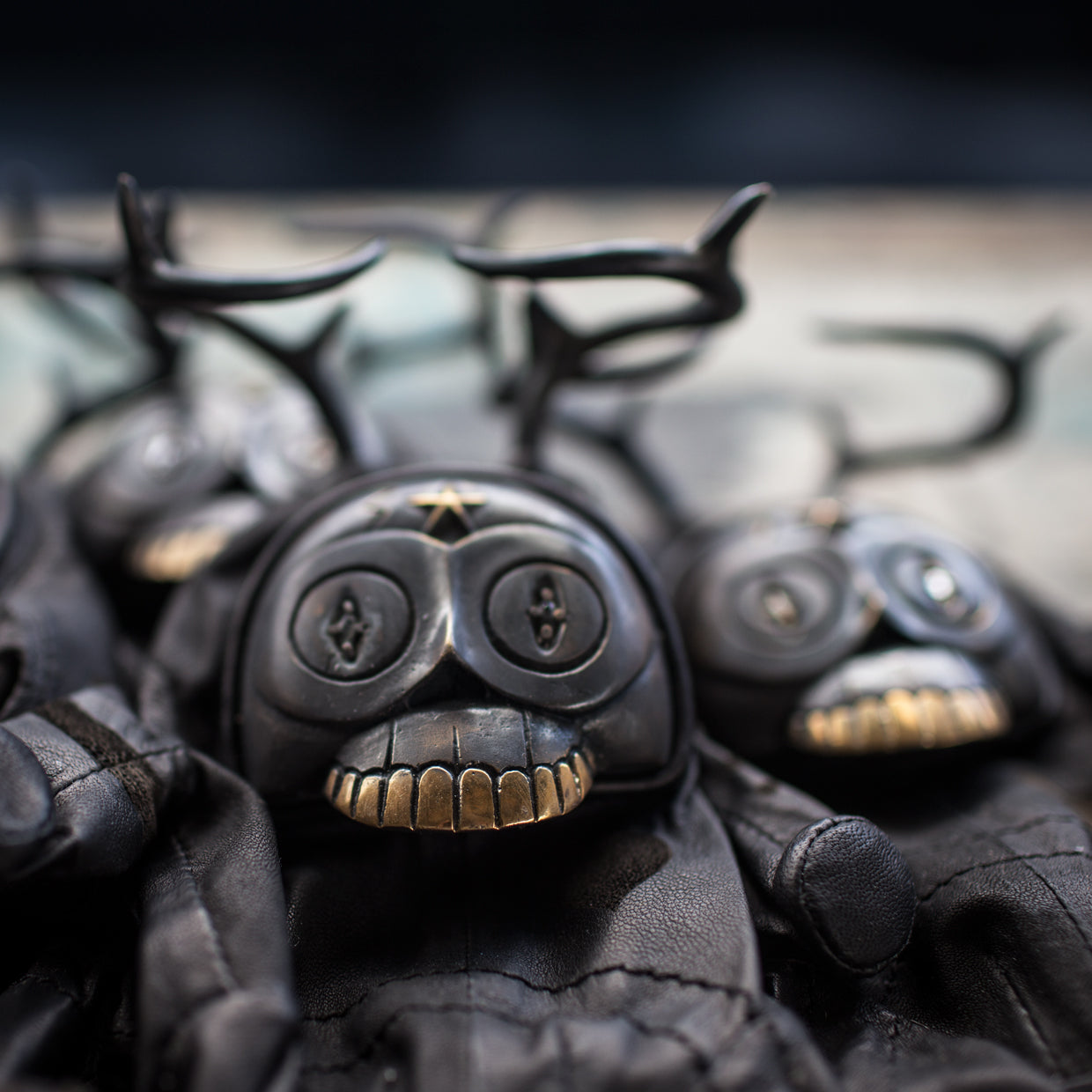Group of black leather and brass figurine heads with a blurred background 