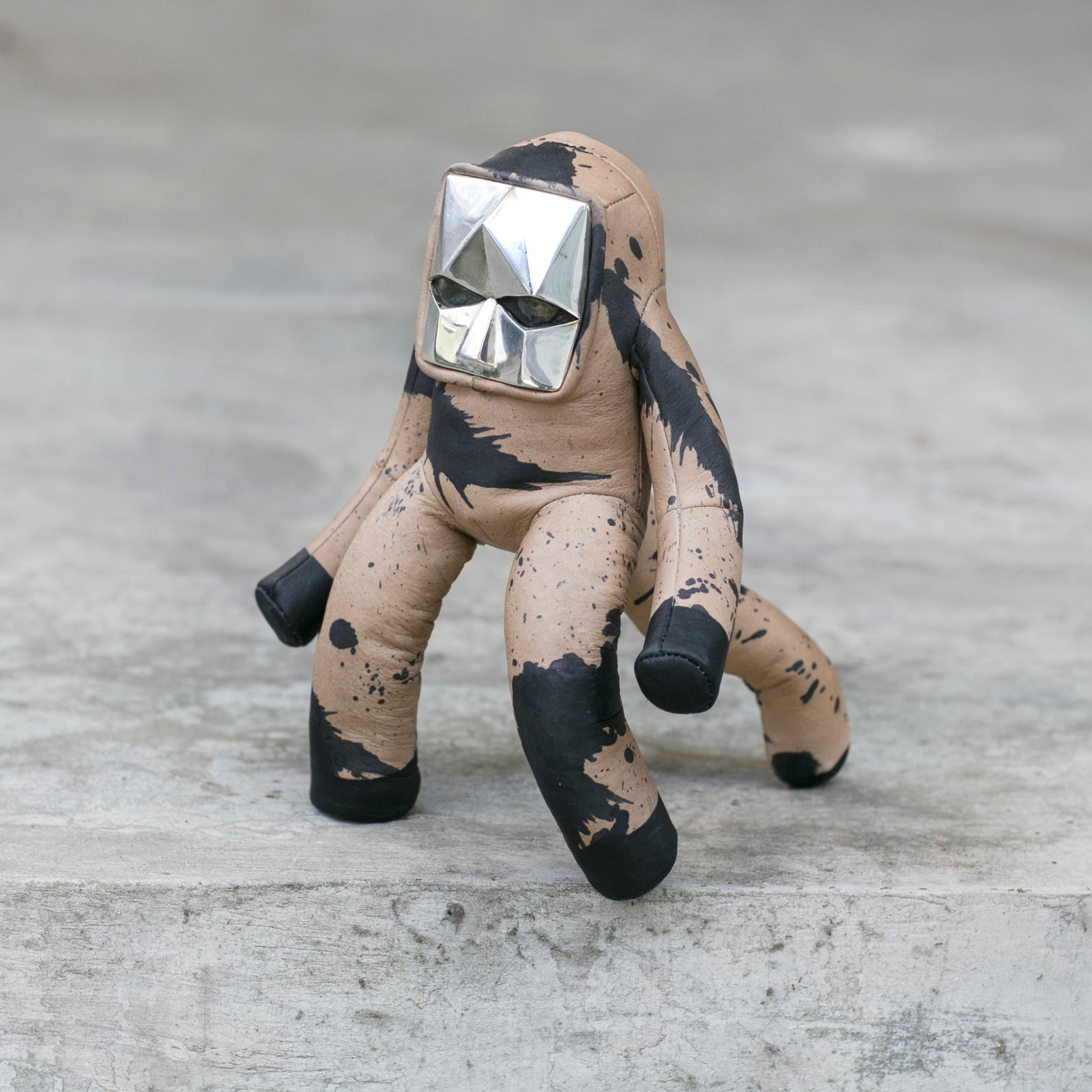 BLAMO Space Baby Splat, a leather toy with a beige and black splattered design and a silver geometric headpiece.