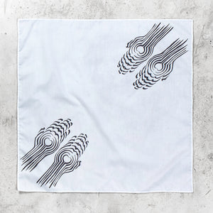 A square white fabric bandana featuring two black abstract spiral patterns, laid flat on a textured gray concrete surface.