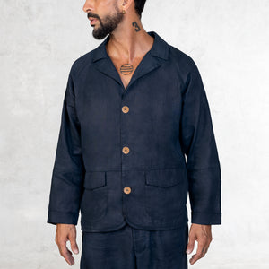 A man facing front from the waist up in an Indigo linen button up suit jacket with 3 large copper button closure