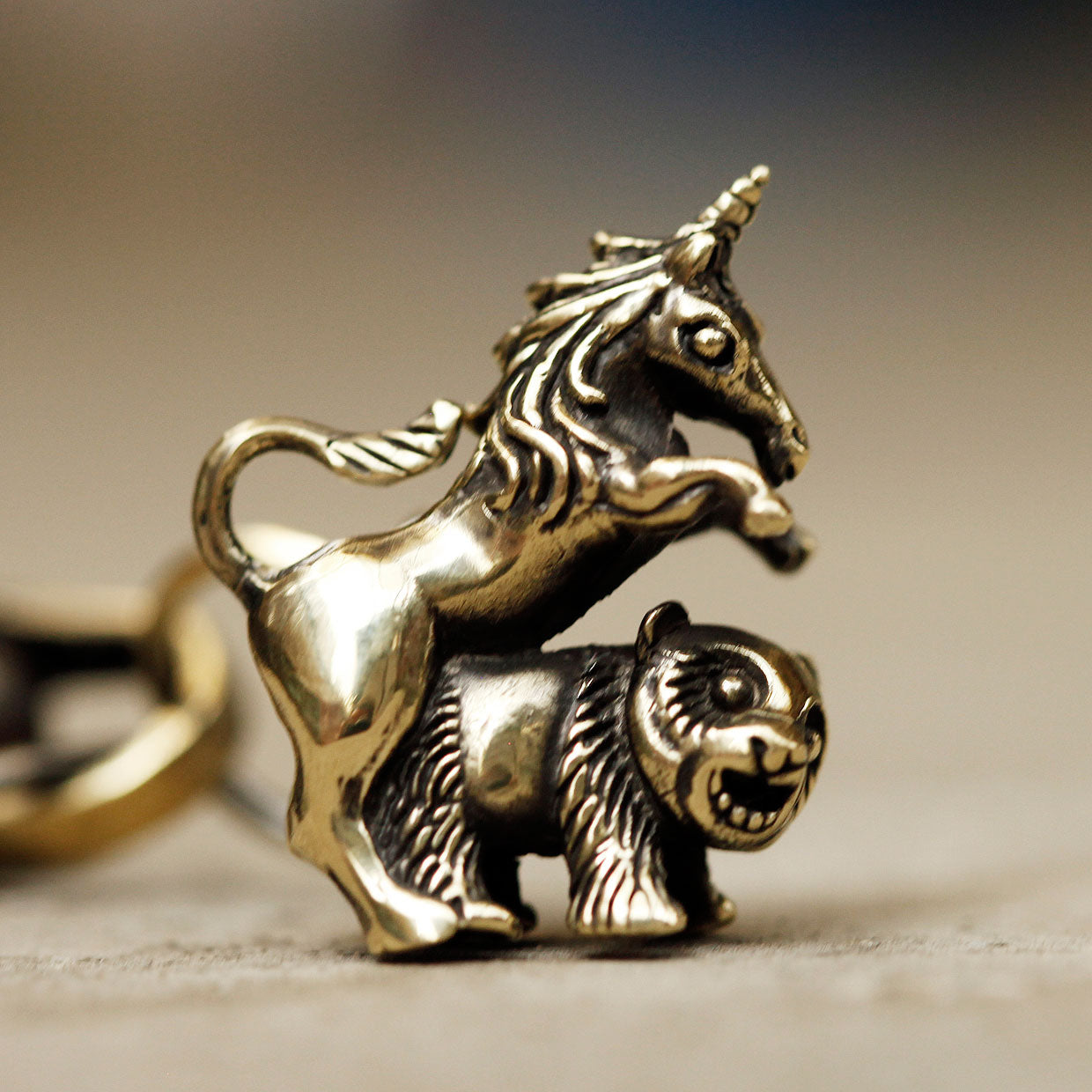 Brass unicorn and panda charm pendant with a blurred background